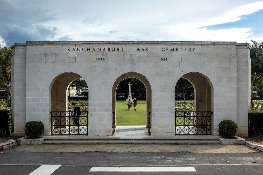 「KANCHANABURI WAR CEMETERY」と刻まれた連合軍共同墓地の門と、アーチ越しの墓石の列